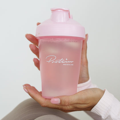 Hand holding a pink protein shaker bottle with 'Protein' branding on a light background