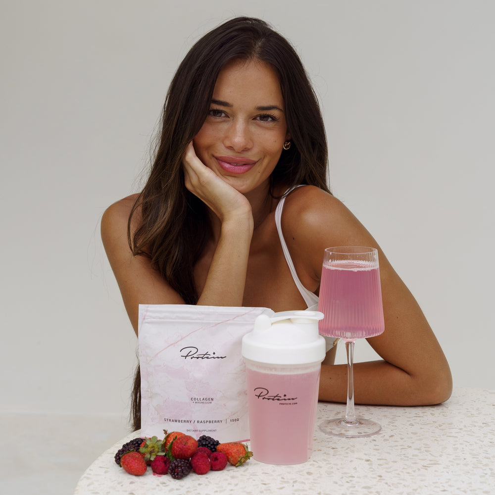 Woman sitting at a table with pink drink, berries, and a container labeled 'Puritane' on a white background.
